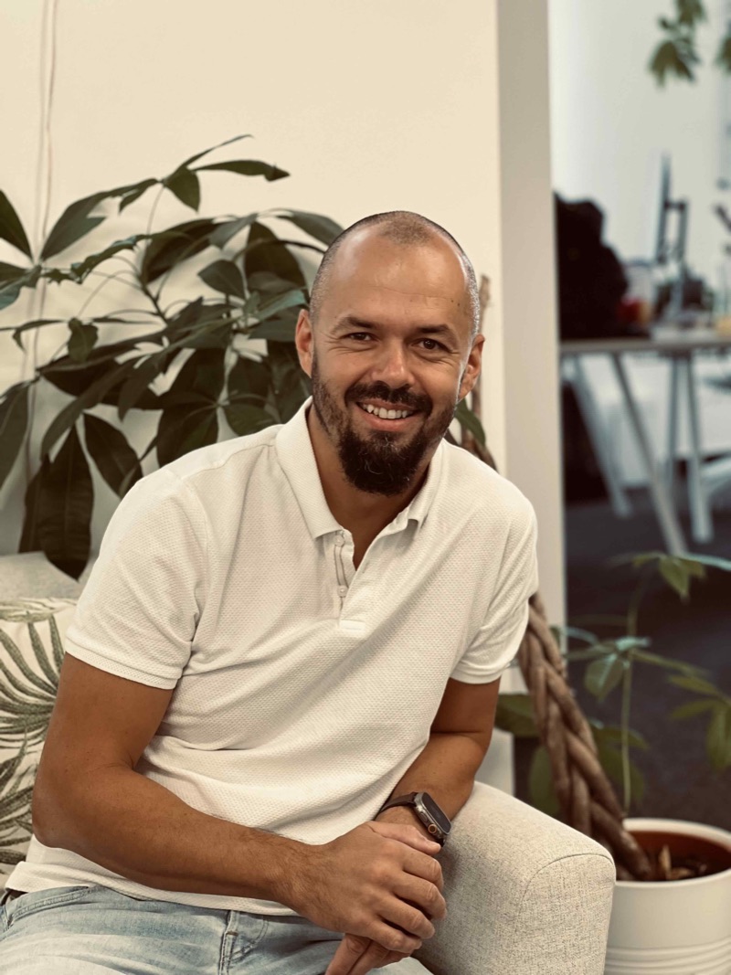 Szabolcs Herman, founder of Drop and SabeeApp, smiling, sitting among plants in the office